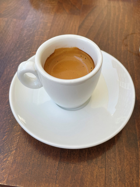 Espresso served in a small white mug and matching saucer.