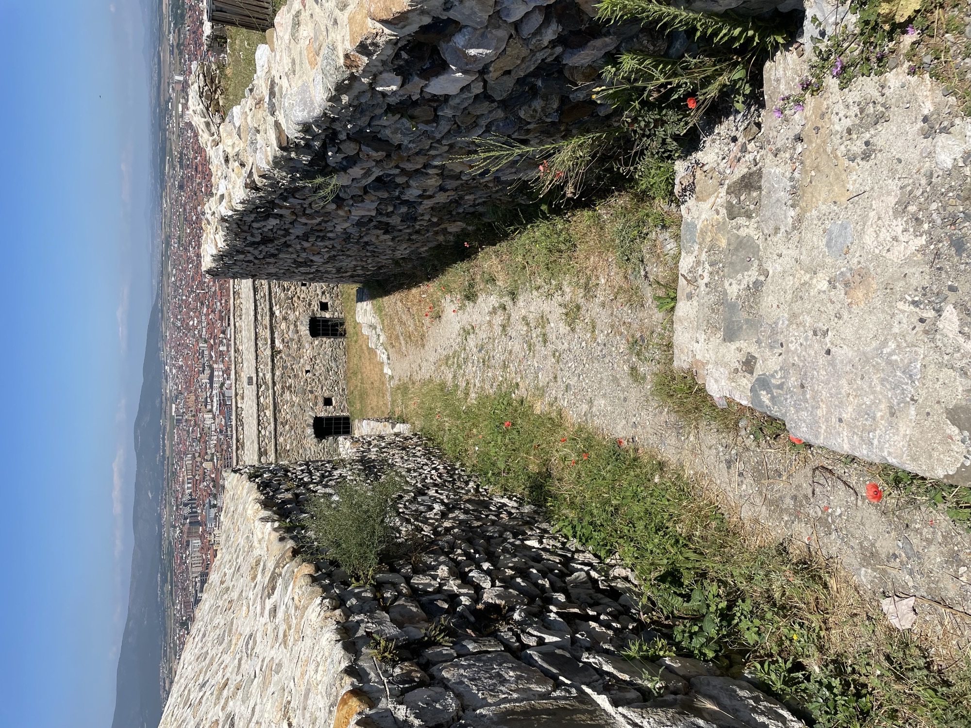 The stone walls of the fortress, with the city of Prizren visible beyond them.