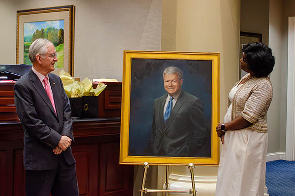 Tommy Norment (left) and Alexis Swann stand next to a portrait of Alvin P. Anderson